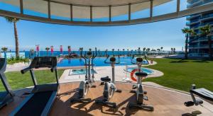 a gym with cardio equipment next to a swimming pool at Sea Senses Blue Ocean in Torrevieja