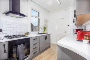 a white kitchen with a stove and a sink at Stylish 3 Bedroom Central Property in Newcastle under Lyme