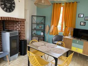 - un salon avec une table, des chaises et une horloge dans l'établissement Le logis d’Aimé, à Saint-Blimont