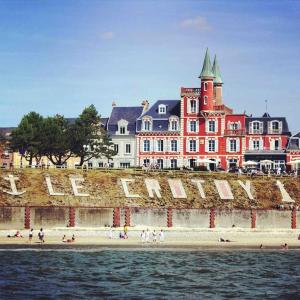 un groupe de personnes sur une plage près d'un grand bâtiment dans l'établissement Le logis d’Aimé, à Saint-Blimont