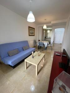 a living room with a blue couch and a table at Alpen1 Paseo Marítimo in Peniscola