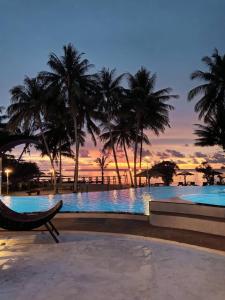 una piscina con palmeras y una puesta de sol en Suanya Kohkood Resort and Spa en Ko Kood