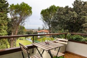 drewniany stół i krzesła na balkonie z drzewami w obiekcie We Home - RICCIONE LOFT Altavilla w mieście Riccione
