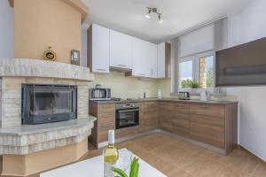 a large kitchen with white cabinets and a fireplace at Villa Filo Apartments in Umag