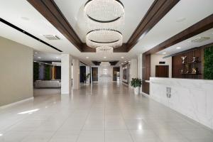 a lobby with a large white tile floor and a chandelier at Hotel Srbija Lux in Stara Pazova