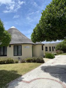 a house with a thatch roof and a driveway at Kelp Cottage - Two Private Garden en-suite Rooms in Gansbaai