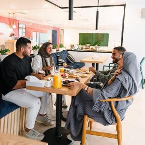 un grupo de hombres sentados en una mesa comiendo comida en Dara Hotel Qurtubah en Riad