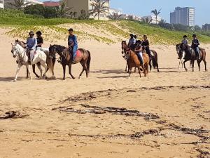 a group of people riding horses on the beach at Barefoot Bungalo in Amanzimtoti