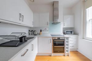 a white kitchen with white cabinets and a stove top oven at Stayo Oxford Street in London