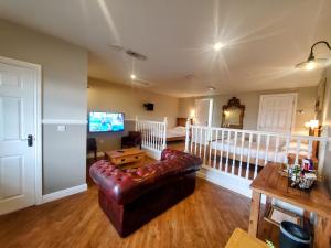 a living room with a leather couch and a bed at The Golden Ball Cottages in Morecambe