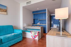 a living room with a blue couch and a kitchen at Estival Islantilla in Islantilla