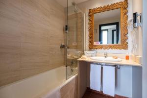 a bathroom with a sink and a tub and a mirror at Estival Islantilla in Islantilla