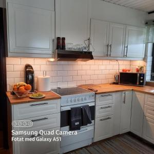 La cuisine est équipée de placards blancs et d'un four avec plaques de cuisson. dans l'établissement Naturnära dubbelrum B&B i Uppsala Ramstalund, à Uppsala