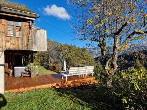 eine weiße Bank auf einer Holzterrasse neben einem Haus in der Unterkunft Gstaad Paradise View Chalet with Jacuzzi in Rougemont