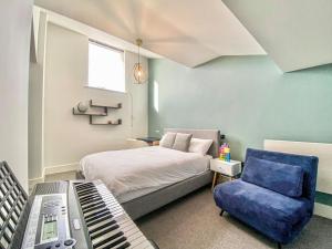 a bedroom with a bed with a keyboard and a chair at Linnet Cottage in Somerford Keynes