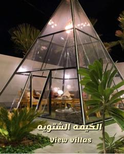 un restaurante con cúpula de cristal y mesa. en View Villas en Buraidah