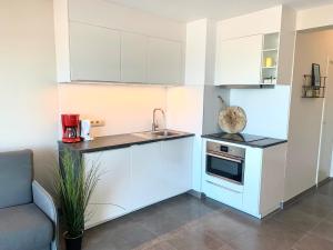 a small kitchen with white cabinets and a sink at studio Zeedijk Emperador in Middelkerke