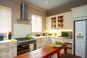 a kitchen with white cabinets and a wooden table at Pete's Place in Durban