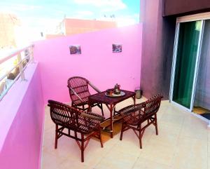 una mesa y sillas en un balcón con una pared rosa en Appartment Majorelle entier au Centre Ville Kenitra en Kenitra