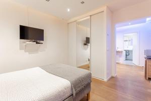 ein weißes Schlafzimmer mit einem Bett und einem TV in der Unterkunft Victor Hugo Flat in Paris