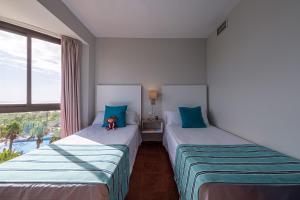 two beds sitting in a room with a window at Estival Islantilla in Islantilla