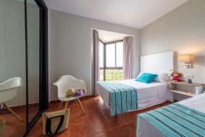 a bedroom with two beds and a chair and a window at Estival Islantilla in Islantilla