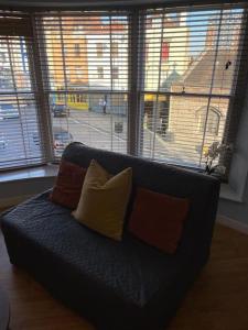 a couch with three pillows in a living room with windows at The Thisle in Bristol