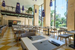 a dining room with tables and chairs and windows at Estival Islantilla in Islantilla