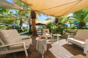 d'une terrasse avec des chaises, une table et des palmiers. dans l'établissement Estival Islantilla, à Islantilla