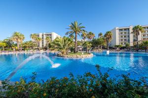 uma grande piscina com palmeiras e edifícios em Estival Islantilla na Islantilla