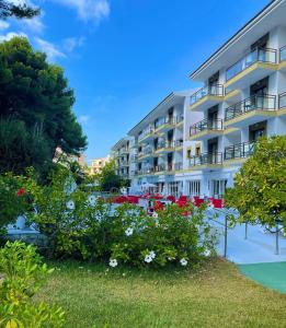 a large white building with flowers in front of it at Guya Wave Hotel in Cala Ratjada