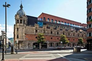 an old brick building with a clock tower on a street at Azkuna Comfort Bilbao in Bilbao