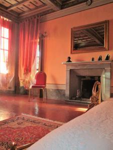 a living room with a fireplace and a red chair at Villa Cantoni in Gropello Cairoli