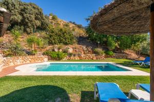 una piscina en un patio con sillas azules en El Chorro Villas Casa Buganvilla, en El Chorro