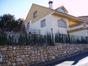 a white house with a fence and a stone wall at Magnífico chalet entre Sierra Nevada y Granada in Dúdar