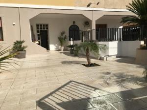 a courtyard with palm trees and a building at Scogliera apartments in Avola