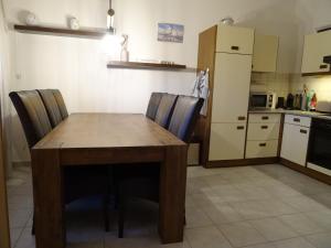 uma cozinha com uma mesa e cadeiras de madeira e um frigorífico em Nord-Ostsee-Nest em Tarp