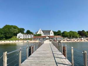 eine hölzerne Promenade, die zu einem Strand und Gebäuden führt in der Unterkunft Ferienwohnung "Fördekieker" in Ulstrupfeld