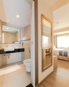 a bathroom with a toilet and a sink and a bed at Mila Hotel in Kathmandu