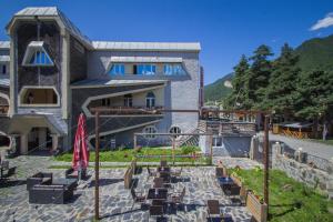 - un bâtiment avec une terrasse et une cour avec des chaises dans l'établissement Hotel Svaneti, à Mestia