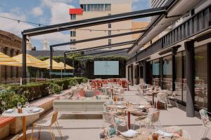 un patio restaurante con mesas, sillas y una pantalla en Hyatt Regency Brisbane en Brisbane