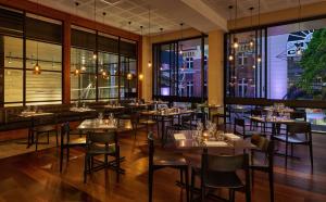 a restaurant with tables and chairs and windows at Hyatt Regency Brisbane in Brisbane
