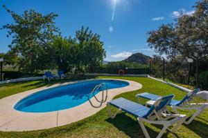 una piscina con 2 sillas de césped y un bluevisorvisorvisor en El Chorro Villas Casa Adelfa, en El Chorro