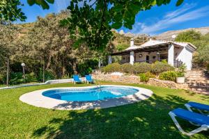 エル・チョロにあるEl Chorro Villas Casa Adelfaの椅子と家のある庭のプール