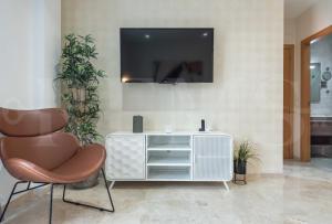 ein Wohnzimmer mit einem Stuhl und einem TV an der Wand in der Unterkunft Lovely duplex with private parking near city center by REMS in Málaga