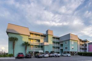 a building with cars parked in a parking lot at Sandpebble Beach Club Surfside Beach a Ramada by Wyndham in Myrtle Beach