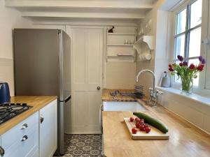 uma cozinha com um frigorífico e uma tábua de cortar com legumes em The Deal Retreat em Kent