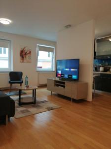 ein Wohnzimmer mit einem Flachbild-TV und einem Tisch in der Unterkunft Apartment Tesla in Wien