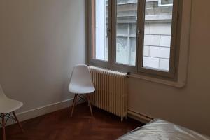 1 dormitorio con una silla blanca y una ventana en Appart grand standing, centre historique climatise, en Aviñón