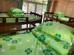 a room with four beds with green sheets and flowers at Pinaski 57-1 in Binlang